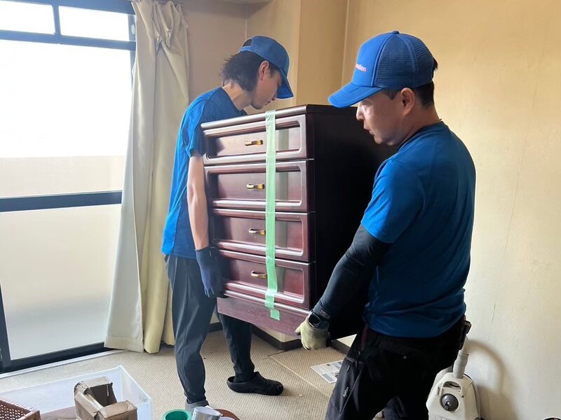 お住まいから桐たんすを二人がかりで運び出すスタッフ
