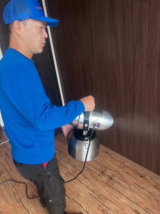 室内で手持ちの噴霧器を使い、消臭・除菌の薬剤を散布するスタッフ