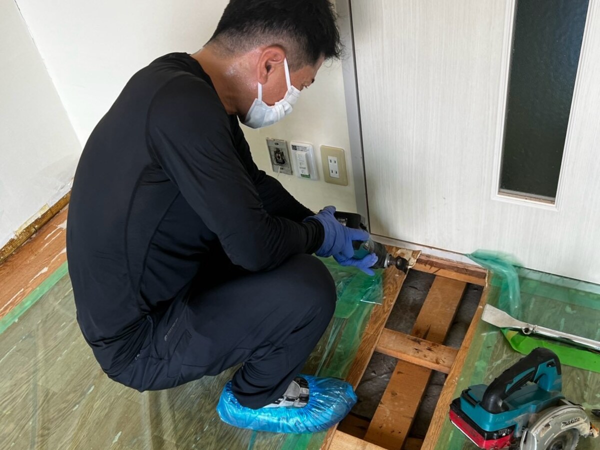 養生シートを敷いた室内で、汚染した床材を撤去するスタッフ