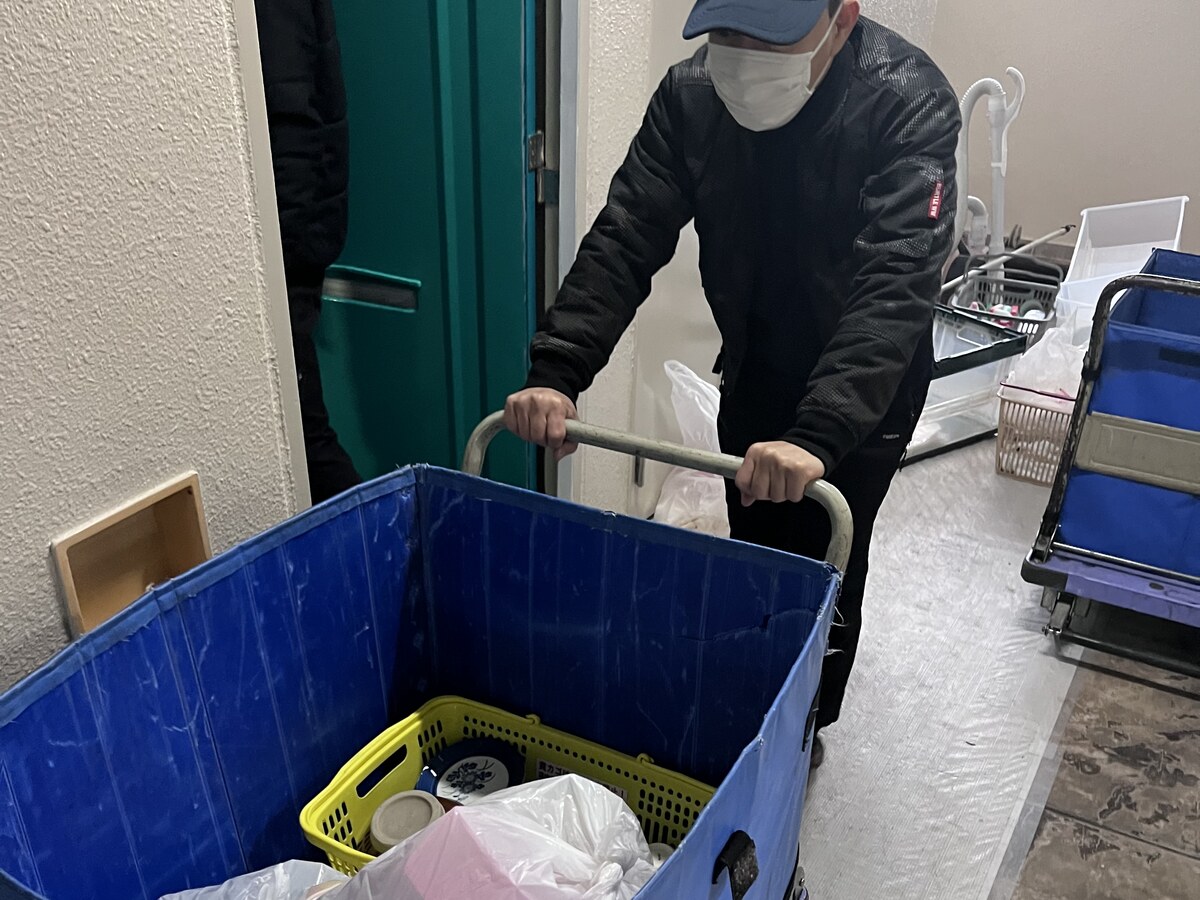 カゴ台車に不用品を積んで運び出すスタッフ