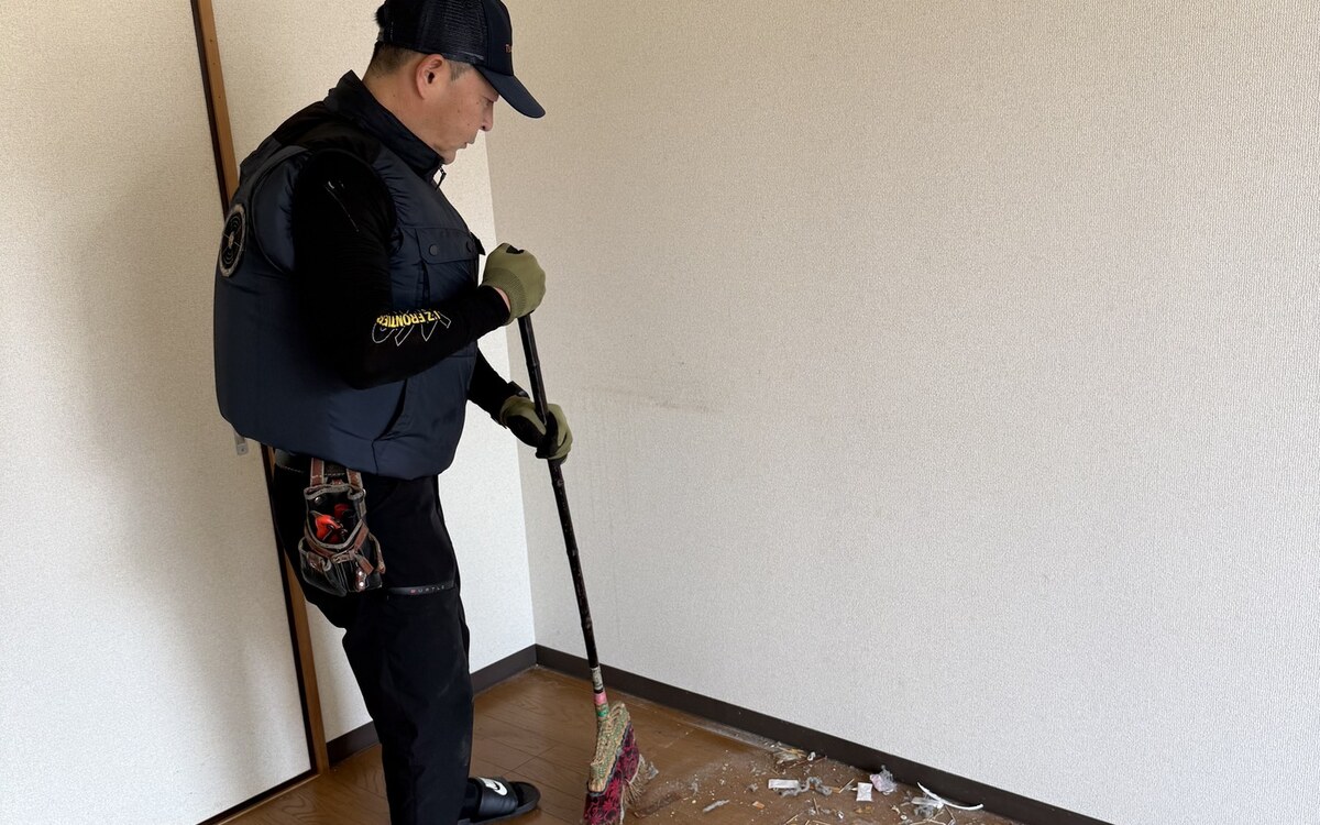 整理後のお部屋をほうきで清掃するスタッフ