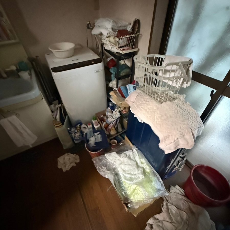 整理前の洗面所。洗濯機のまわりにお荷物が置かれている状態(尼崎市)